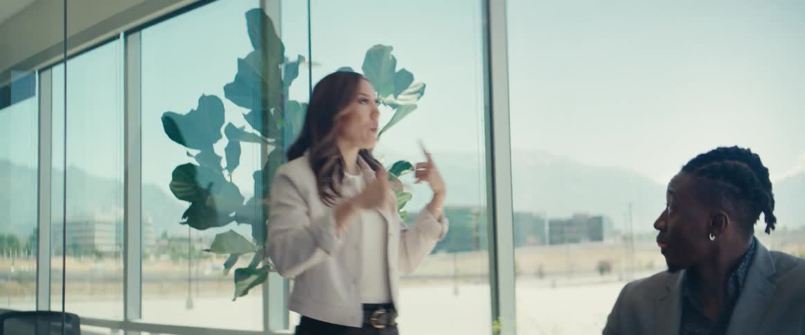 An asian woman talks with a black man while walking in an office