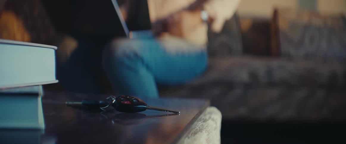 Person quickly picking up a car key from a wooden table