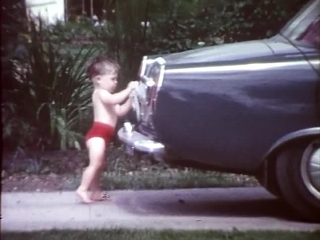 A toddler washes a vintage car