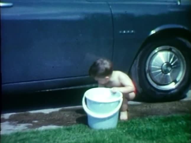 Little boy carries heavy bucket of water