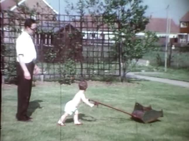 Father teaches his son to mow the lawn