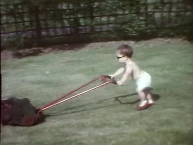 A baby in sunglasses mowing the lawn