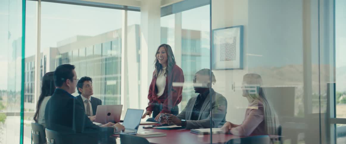 Coworkers smile during a discussion at a meeting in the office on a sunny day