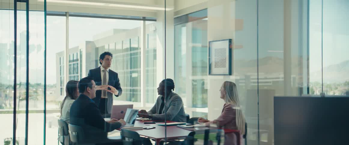 Man in suit standing in a meeting with other people talking