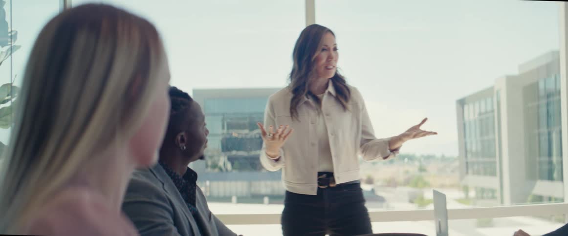 An asian speaks to people sitting in an office