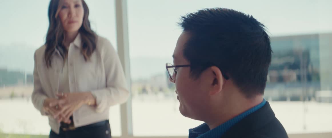 Woman standing talking to a man who is sitting in an office room