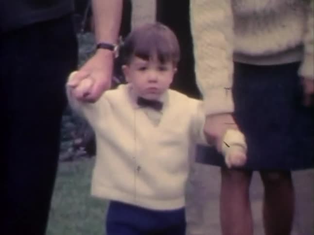 Little boy holding hands with his parents walking
