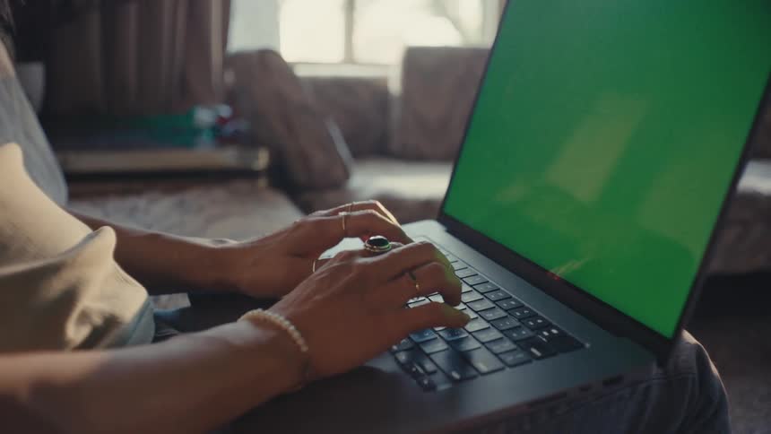 Person sitting in living room typing on laptop