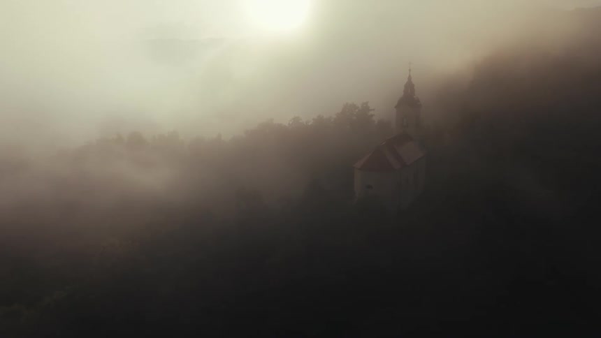 A church with a prominent steeple emerging from a dense fog