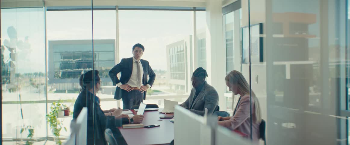Colleagues gathered around a table in a modern office with large windows in a business meeting