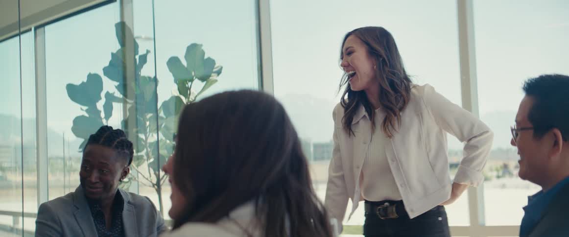 Colleagues gathered around a table in a modern office with large windows in a business meeting