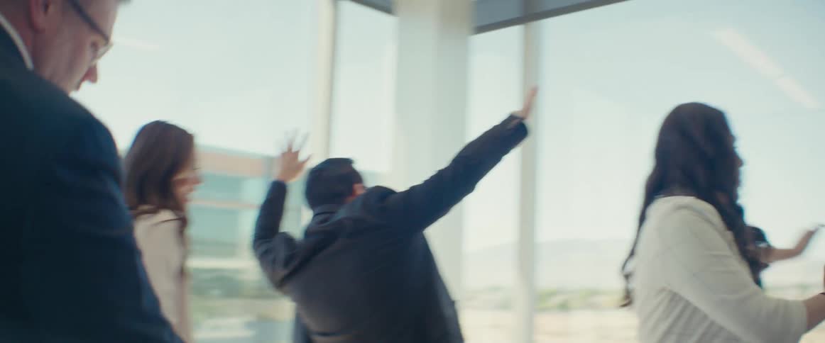 Coworkers dance while in a meeting room in their office building