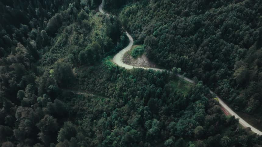 Aerial view of a highway winding through the mountain with trees around