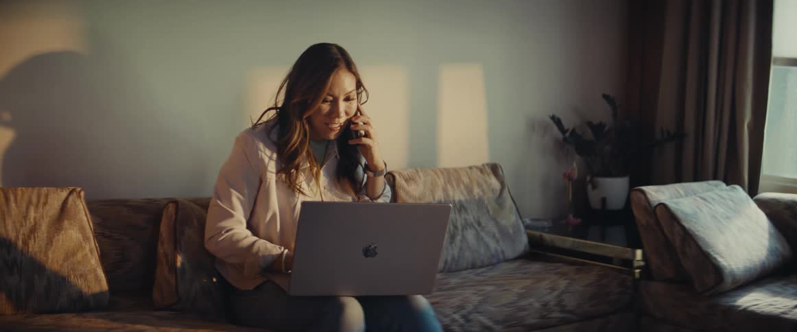 A woman picks up her cell phone and laptop and leaves the room