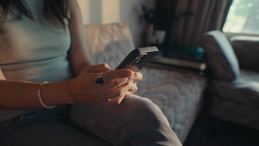 A woman is using her cell phone on the couch