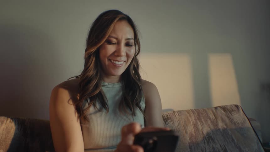 Woman sitting on the couch interacting with an iphone