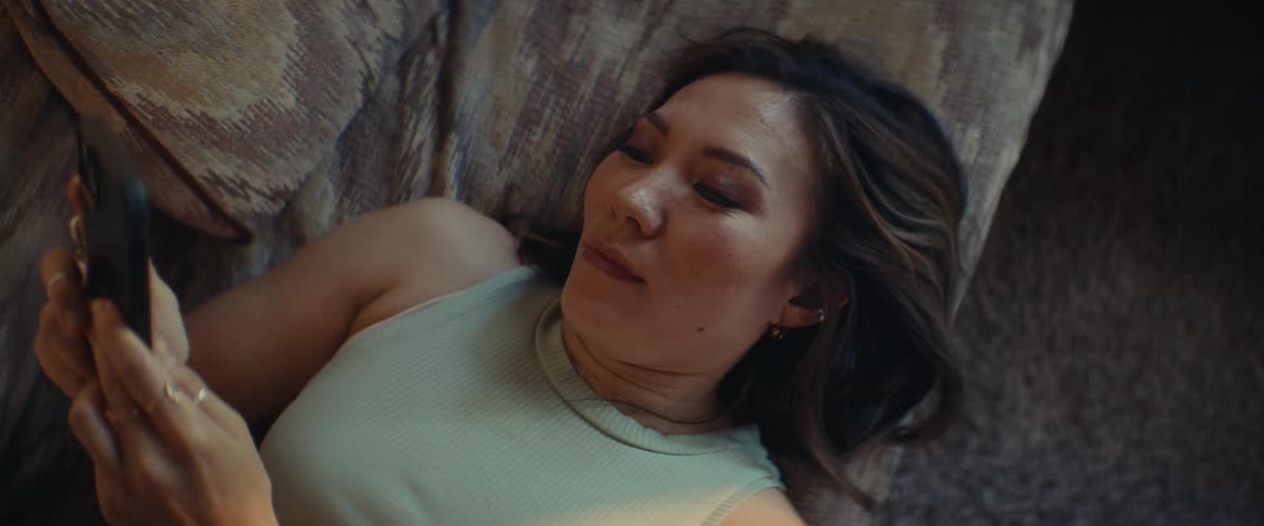 Woman lying down interacting with an iphone with a happy facial expression