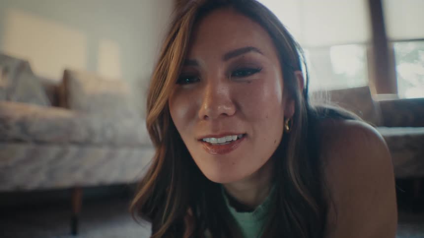 Closeup of a womans face as she looks at a screen while lying on the living room floor