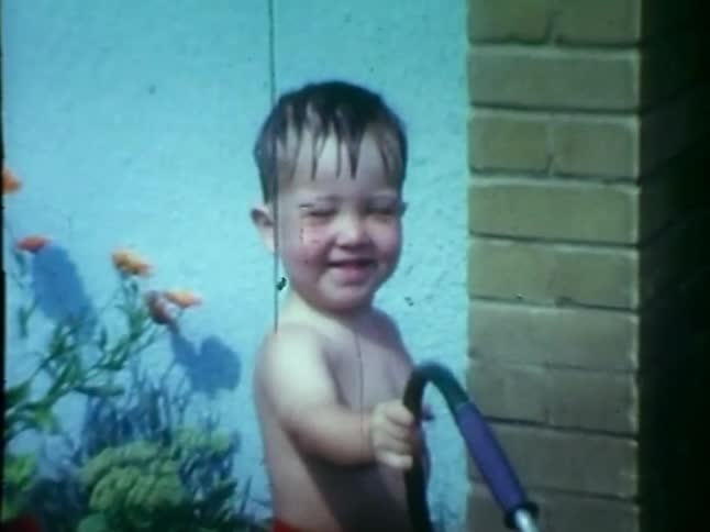 Smiling boy plays with a hose