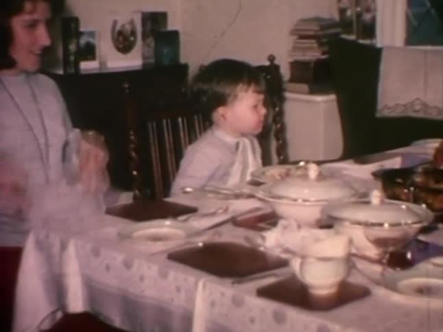 A happy toddler eats while adults serve food