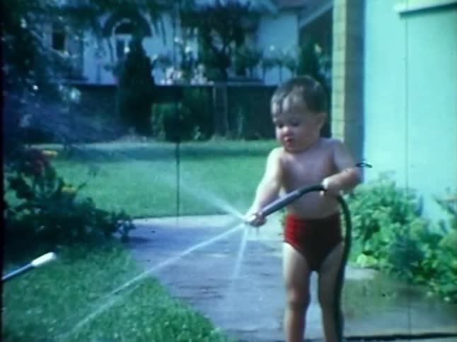 A toddler spraying water and laughing