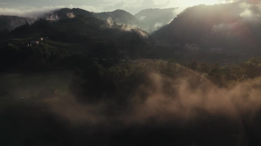 The sun is starting to rise above a range of mountains that line a valley