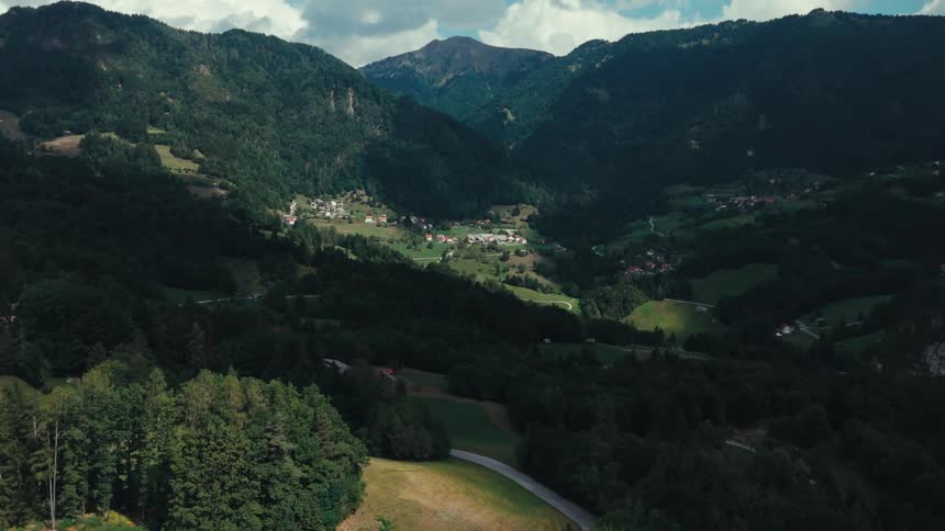 Aerial of mountains covered in trees with rural towns in the valleys between them