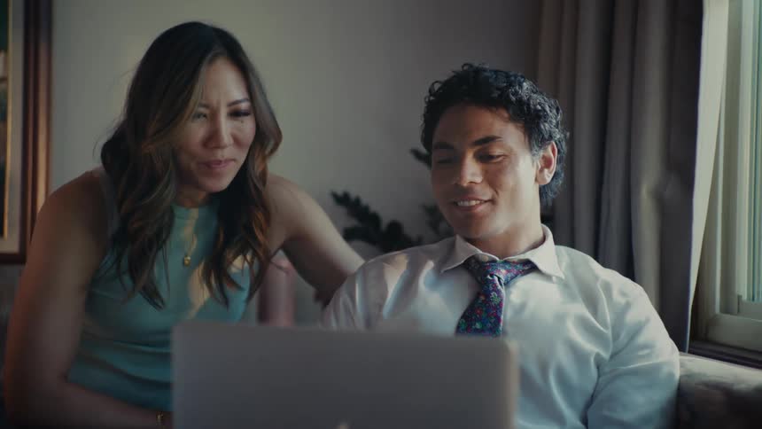 Woman sitting next to a man who is using a laptop