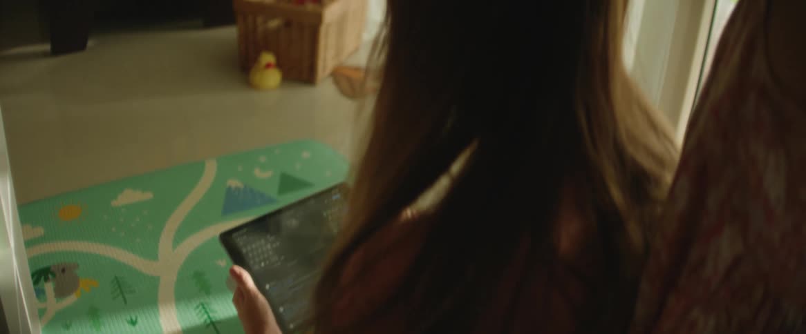 Woman sitting interacting with a tablet and a child playing with her hair