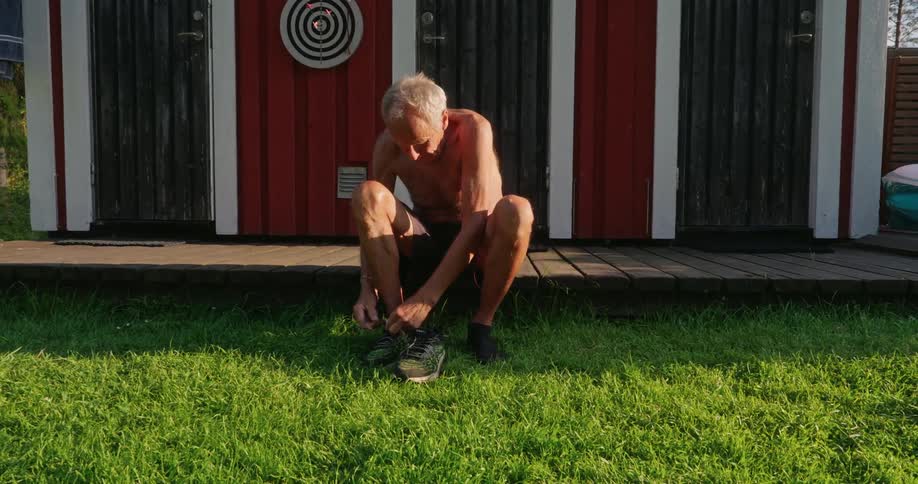 Elderly man sitting tying tennis shoes
