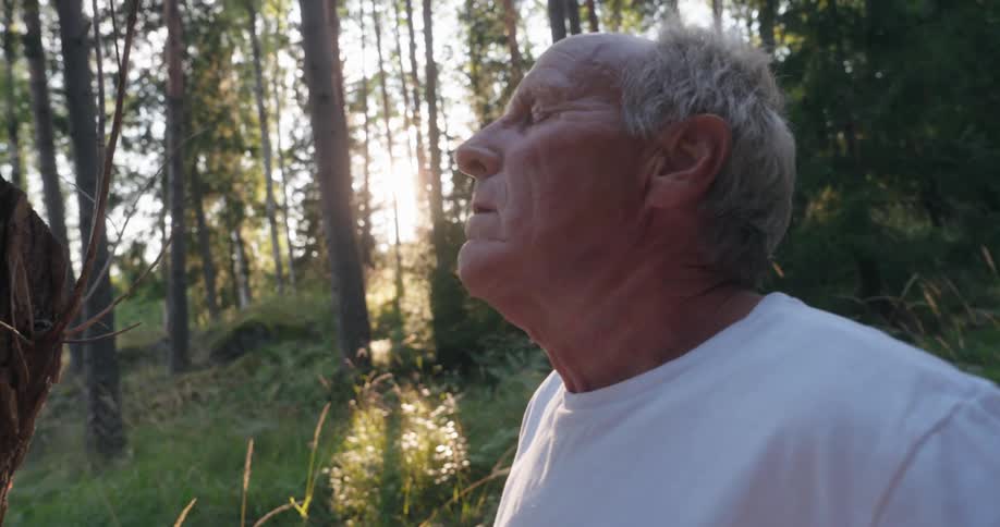 Portrait of an elderly man in the forest taking a deep breath