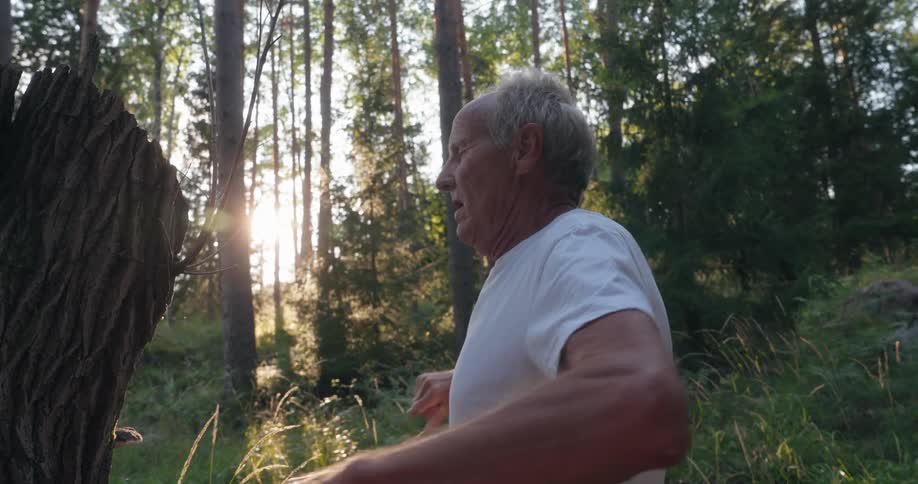 Elderly man in forest stretching his arms