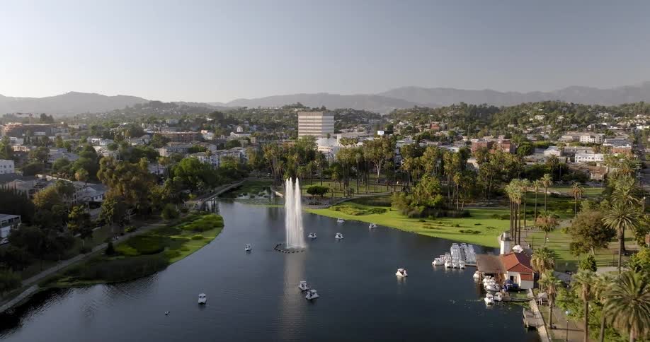 Aerial view of a park with a large pond and a tall fountain in the city