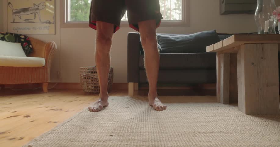 Elderly man stretching his body in the living room