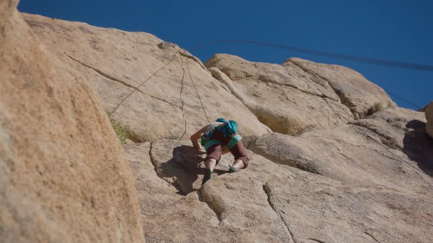 Man climbing a rocky mountain face with equipment