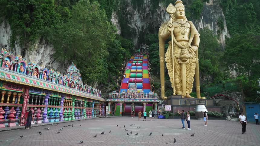 People in an open shrine with a golden statue in the background and mountains