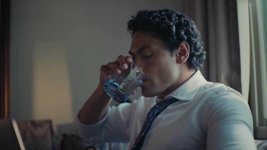 Man drinking water looking at the time on the clock and leaving quickly