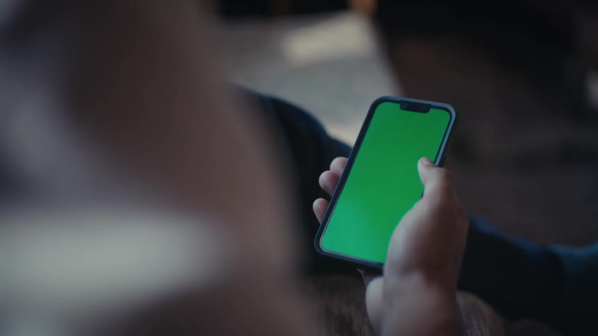 A person uses a smartphone with a green screen then places it face down