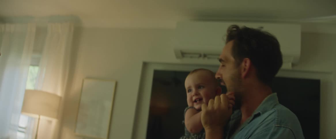 Father holding his baby daughter on his lap playing and the mother next to him having fun together
