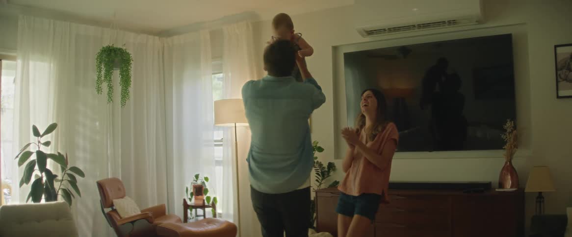 A father holding a baby as they and the mother dance around in their living room