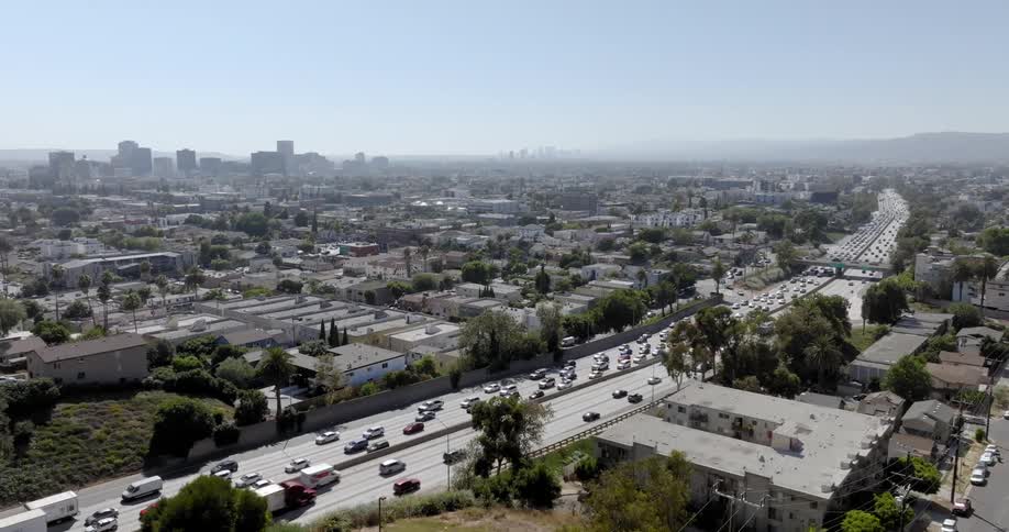Panorama of an urban city with a highway with vehicle traffic and the silhouette of mountains on the horizon