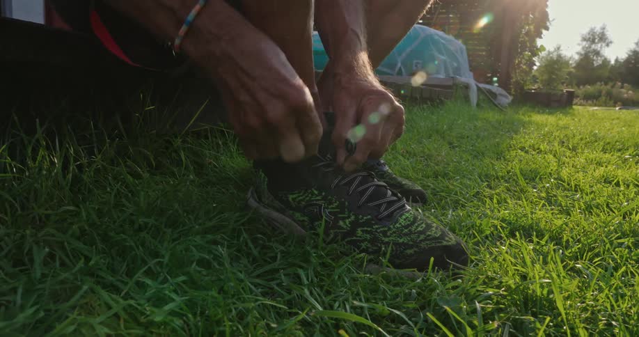Man sits near his rural home tying his shoe lace on a sunny day