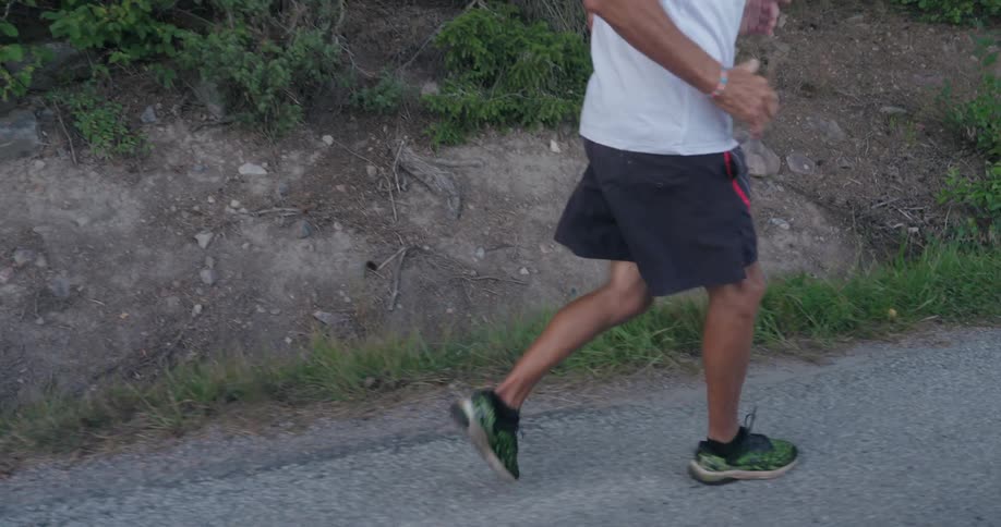 A person is running on a dirt path with vegetation on the sides