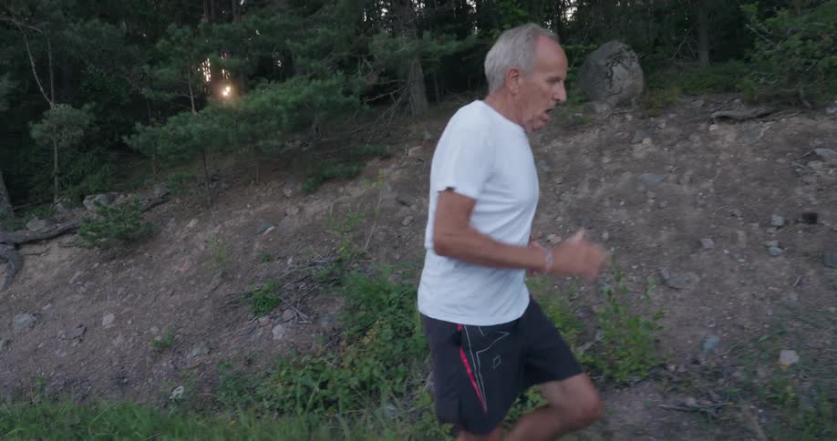 Elderly man in a white shirt running in a natural environment