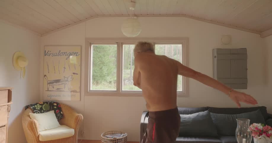 An elderly man exercises in his living room
