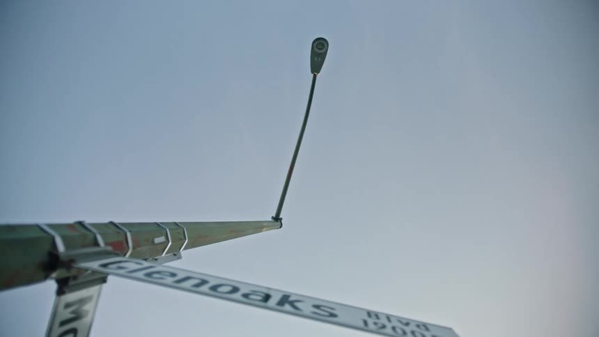 An orbital view looking straight up at a light pole with two road signs on the pole