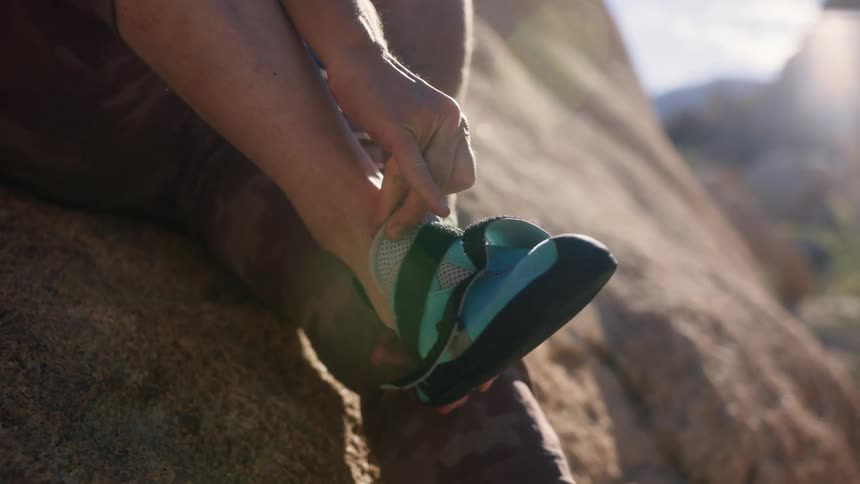 A person is putting on a blue tennis shoe with velcro on his foot