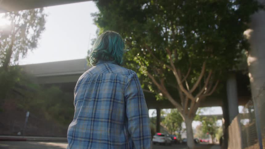 Back view of a person walking through the city with an overpass in front