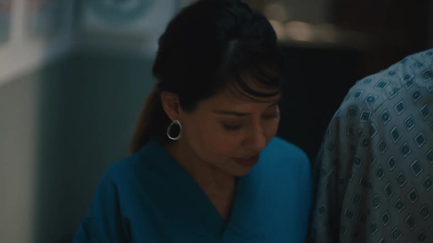 Nurse helping a young man walk down a hospital hallway
