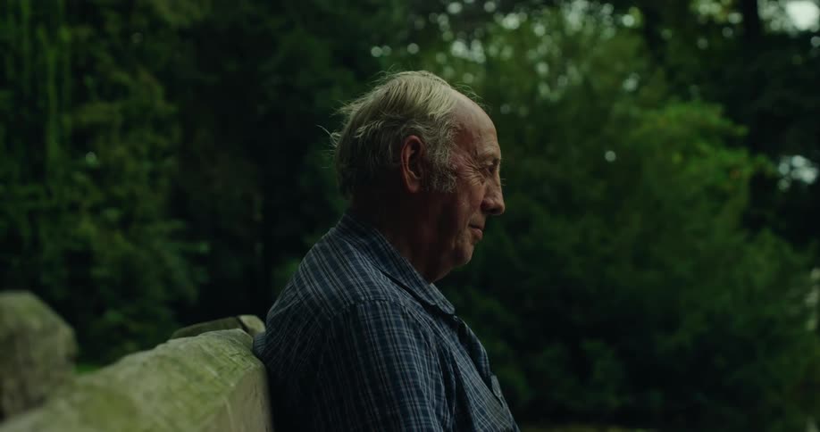 Elderly man sitting on a bench outdoors looking forward